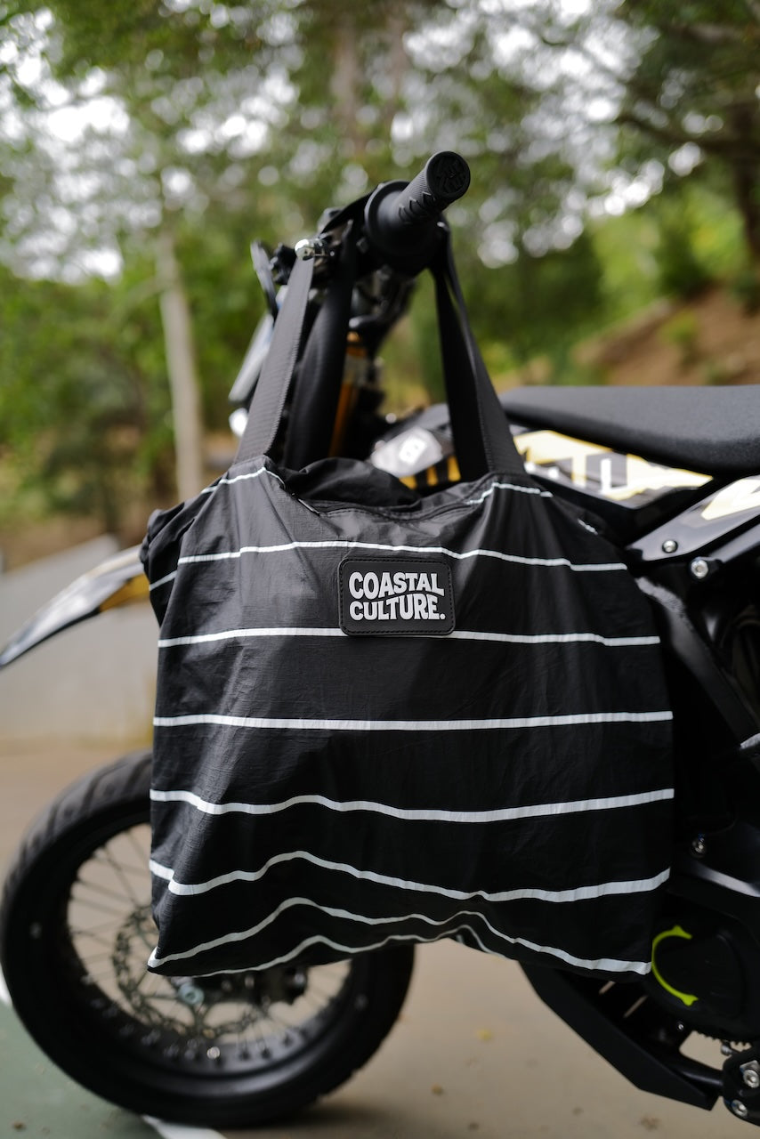 Black and white striped bag with 'Coastal Culture' logo attached to a motorcycle.